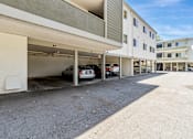 Thumbnail 22 of 43 - A car is parked in a garage attached to a white building.