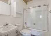Thumbnail 30 of 32 - A white bathroom with a sink, toilet, and shower.