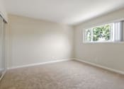 Thumbnail 18 of 37 - A room with a carpeted floor and a window with white curtains.