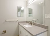Thumbnail 17 of 27 - A white sink in a bathroom with a mirror above it.