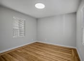 Thumbnail 23 of 31 - A room with wooden flooring and a window with blinds.