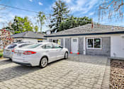 Thumbnail 5 of 21 - A white car is parked in front of a house with a grey roof.