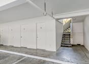Thumbnail 41 of 43 - A room with white walls and a concrete floor with a staircase on the right side.