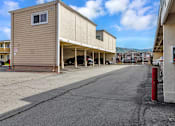 Thumbnail 24 of 40 - A parking lot with a tan building on the left and a red pole on the right.