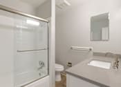 Thumbnail 16 of 27 - A white bathroom with a glass shower door and a white toilet.