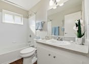 Thumbnail 27 of 33 - A white bathroom with a toilet, sink, and mirror.