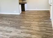 Thumbnail 5 of 7 - an empty living room with wood flooring and a kitchen