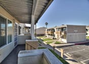 Thumbnail 14 of 33 - A view of a building's patio with a concrete wall and a parking lot in the background.