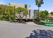 Thumbnail 39 of 92 - A green car is parked on the street in front of a building.