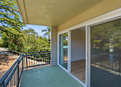 Thumbnail 67 of 92 - A balcony with a sliding glass door leading to a backyard.