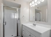 Thumbnail 51 of 51 - A white bathroom with a sink, mirror, and shower.