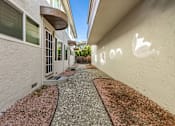Thumbnail 22 of 42 - A pathway with gravel and a wall with a white arrow painted on it.