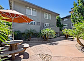 Thumbnail 11 of 32 - A patio with a table and chairs is surrounded by a garden.
