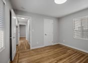 Thumbnail 20 of 31 - A long hallway with white walls and wooden floors.