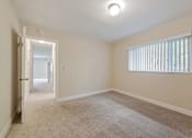 Thumbnail 21 of 29 - A room with a carpeted floor and a window with blinds.