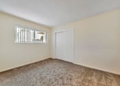 Thumbnail 31 of 43 - A room with a carpeted floor, a white door, and a window with blinds.