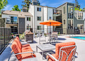 Thumbnail 35 of 41 - A patio with chairs and an umbrella in front of apartment buildings.