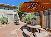 Thumbnail 10 of 32 - A patio with a table and chairs and an umbrella.