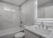 Thumbnail 12 of 31 - A white bathroom with a tub, toilet, and sink.