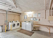 Thumbnail 27 of 42 - A laundry room with washers and dryers and a bench.