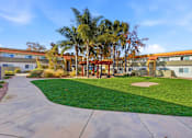 Thumbnail 42 of 67 - A building with a red roof is surrounded by a green lawn and palm trees.
