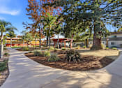 Thumbnail 46 of 67 - A tree-lined walkway leads to a building with a red roof.
