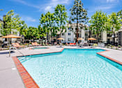 Thumbnail 13 of 41 - A large swimming pool surrounded by trees and apartment buildings.