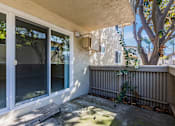 Thumbnail 35 of 51 - A patio with a sliding glass door and a tree.