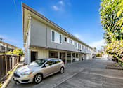 Thumbnail 27 of 42 - A silver car is parked in a driveway in front of a two-story building.