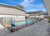 Thumbnail 14 of 44 - A pool surrounded by a black fence in a sunny backyard.