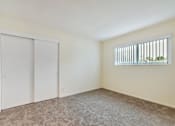 Thumbnail 14 of 43 - A room with a carpeted floor, a window with blinds, and a door.