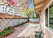 Thumbnail 28 of 42 - A patio with a bench and a tree with pink flowers.