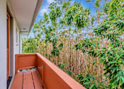 Thumbnail 2 of 29 - A balcony with a bench and a view of trees.