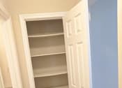 Thumbnail 31 of 42 - A white pantry with a door open to a hallway.