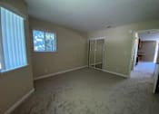 Thumbnail 14 of 26 - A room with a carpeted floor and a window with blinds.