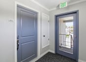 Thumbnail 56 of 92 - A hallway with a blue door and a white door with a window.