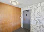 Thumbnail 73 of 92 - A room with a grey door and a stone wall.