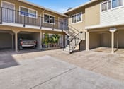 Thumbnail 2 of 17 - A car is parked in the garage of a two-story apartment building.