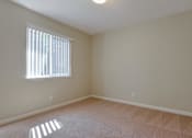 Thumbnail 28 of 34 - A room with a carpeted floor and a window with blinds.