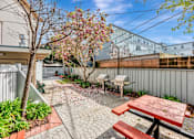 Thumbnail 13 of 42 - A patio with a picnic table and a tree with pink flowers.