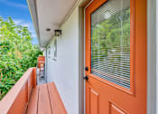 Thumbnail 25 of 29 - A balcony with a wooden bench and an orange door.