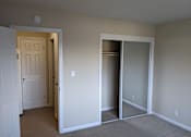 Thumbnail 29 of 42 - A room with a white door and a white closet with a mirror.