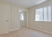 Thumbnail 27 of 34 - A white door is on the left of a room with a carpeted floor and a window with blinds.