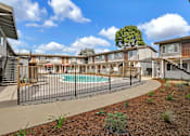 Thumbnail 30 of 38 - A pool surrounded by a black fence and a building in the background.