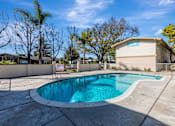 Thumbnail 30 of 51 - A swimming pool in a backyard with a fence and trees.