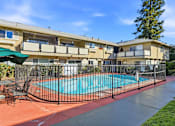 Thumbnail 2 of 33 - A pool surrounded by a black fence and chairs.