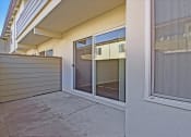 Thumbnail 29 of 35 - A patio with a sliding glass door and a concrete floor.