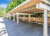Thumbnail 23 of 41 - A parking lot with a white canopy and a wooden fence.