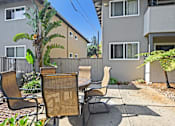 Thumbnail 8 of 37 - A patio with a table and chairs is surrounded by a fence and a tree.
