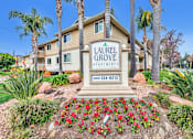 Thumbnail 31 of 62 - A sign for Laurel Grove Apartments stands in front of a building with a flower bed in the foreground.